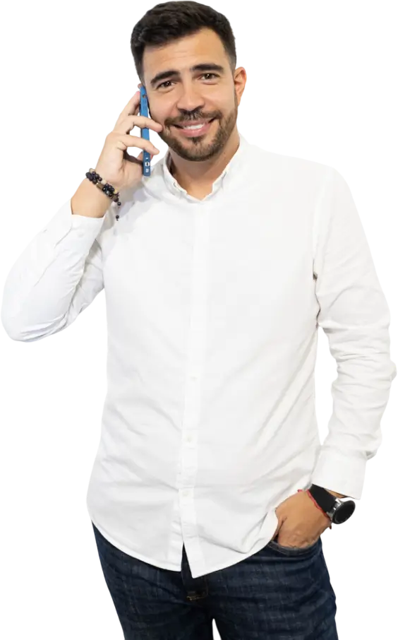 Hombre sonriente con camisa blanca hablando por teléfono móvil, mostrando un estilo casual y profesional.